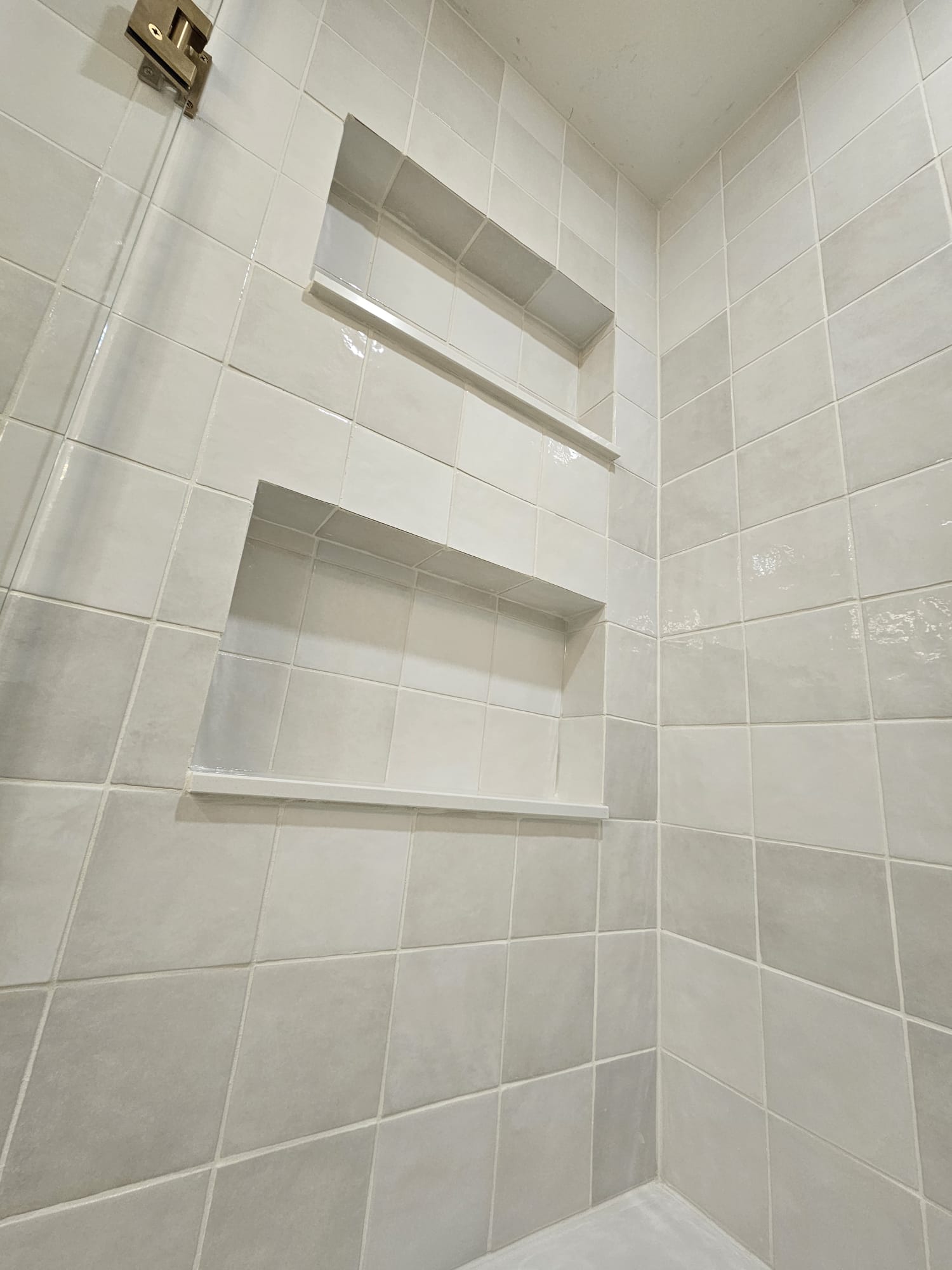White tiled shower with recessed wall shelves