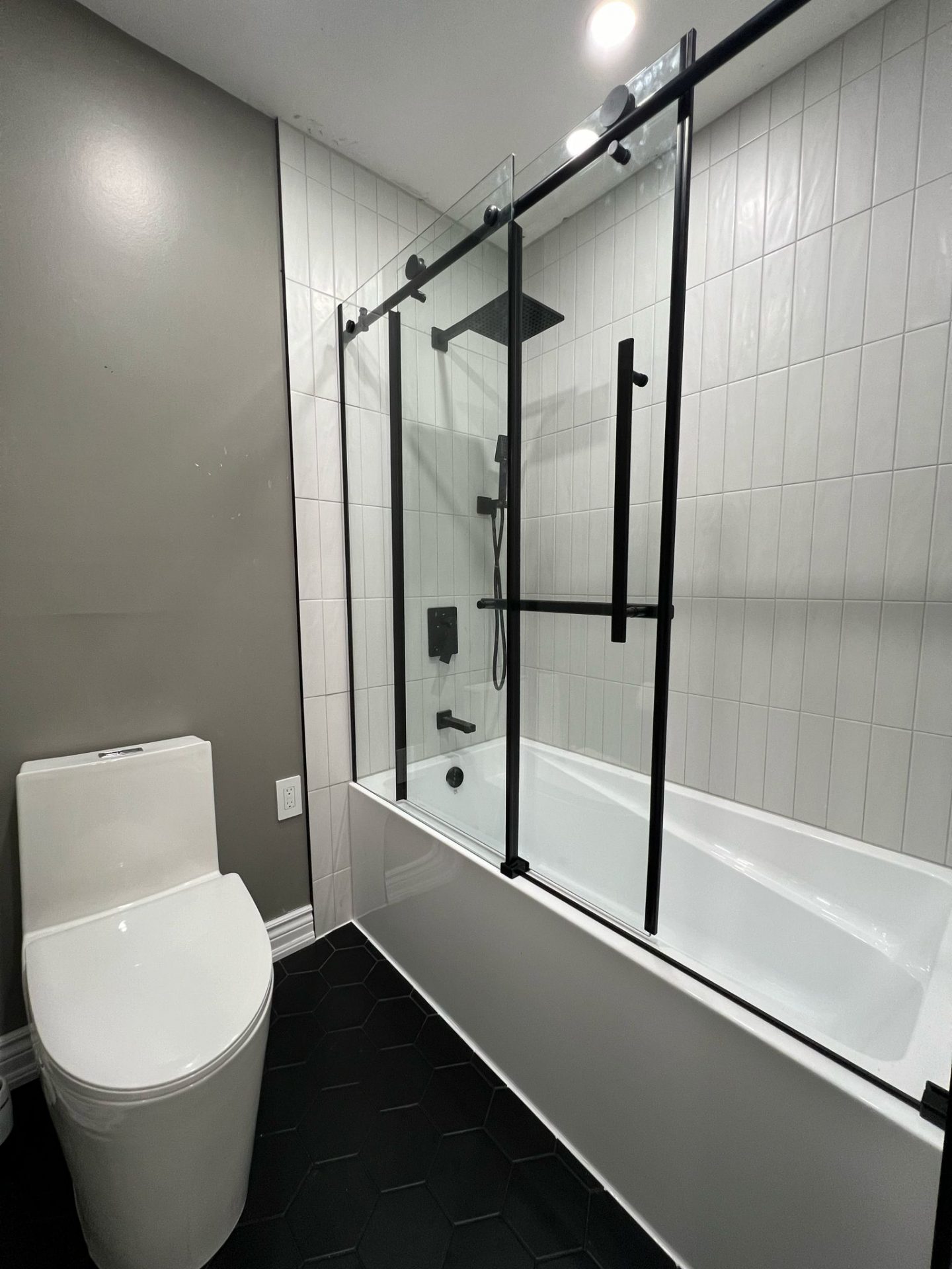 Modern bathtub shower with black glass doors