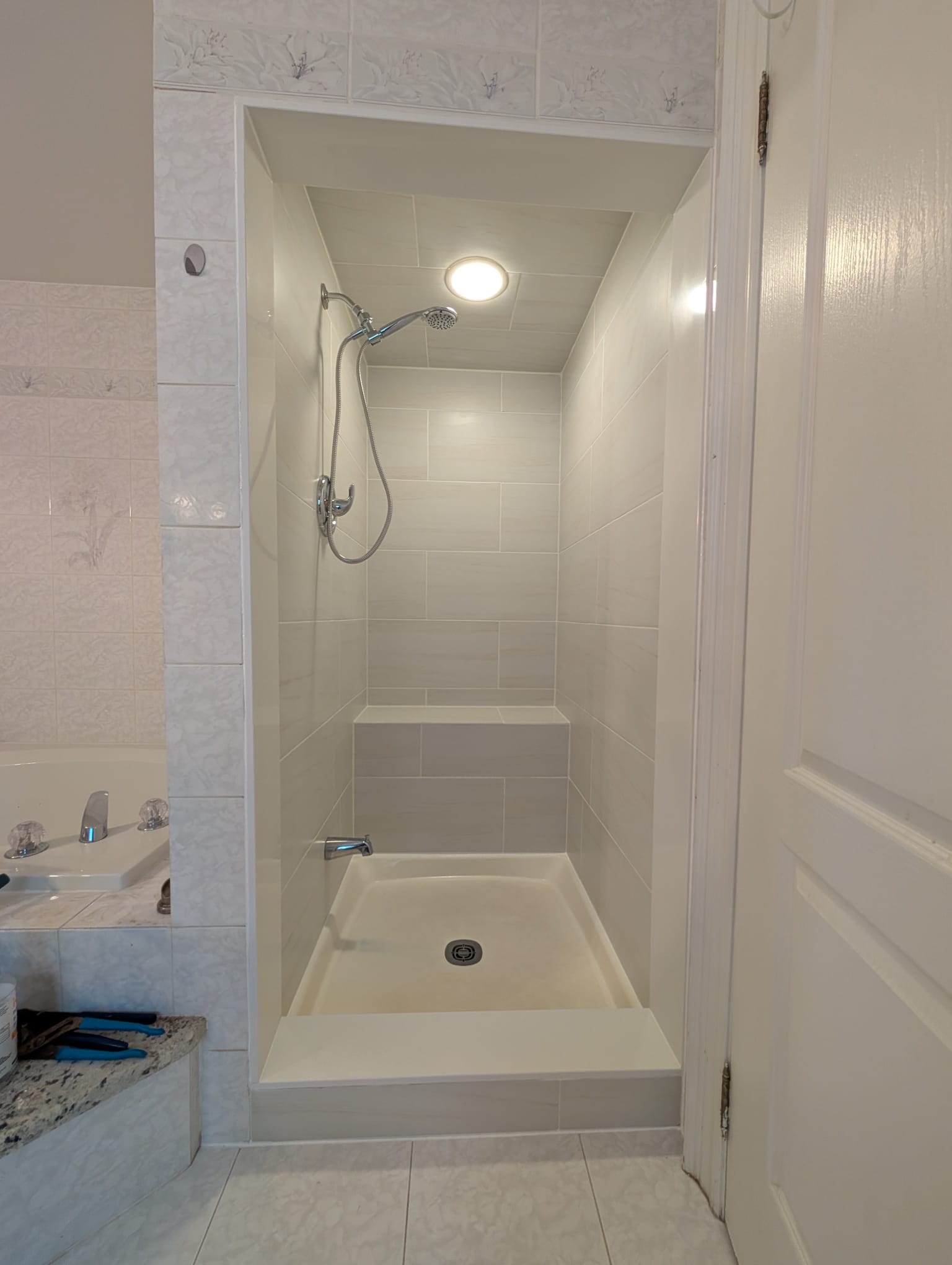 Small tiled shower stall with built-in bench